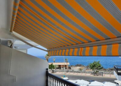 Toldo extensible de lona a rayas instalado en un balcón con vistas en Tenerife